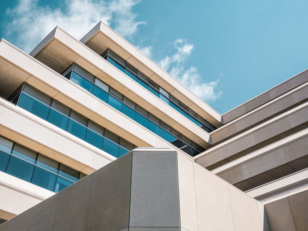Photo by Anthony Esau low angle photo of beige concrete building under cloudy sky