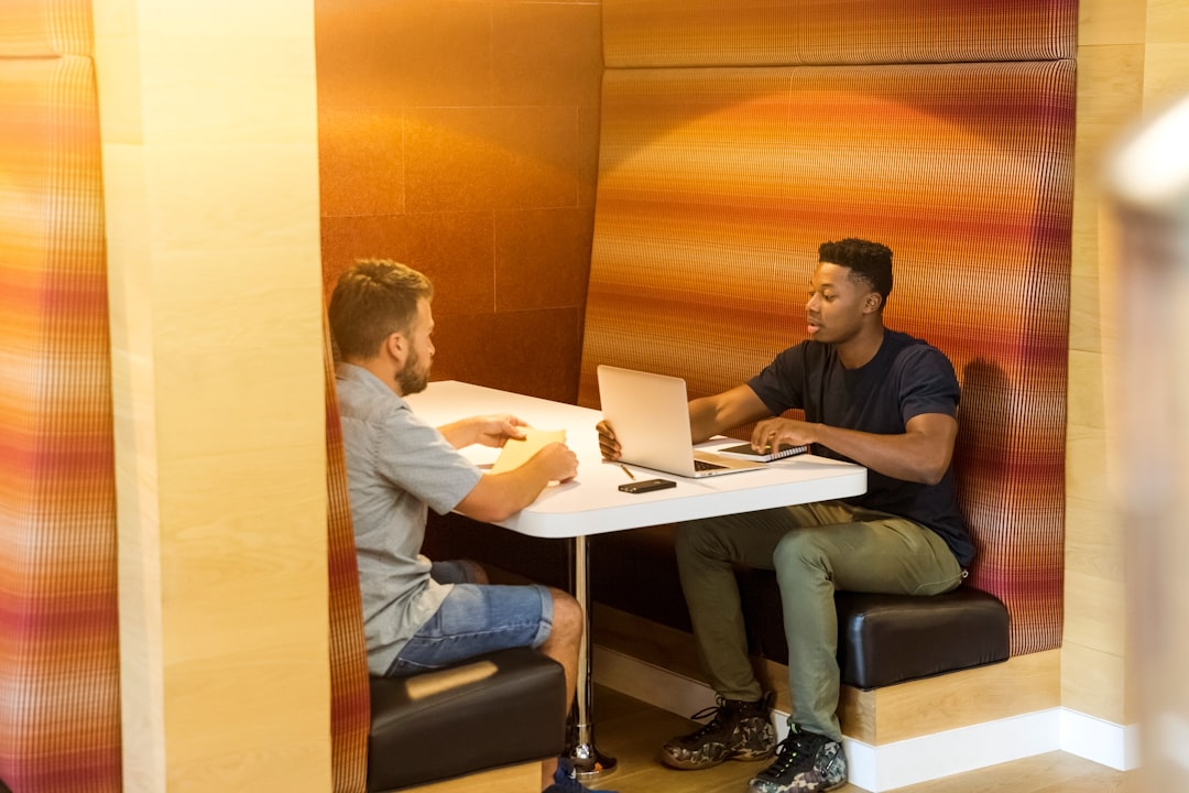 Photo by LinkedIn Sales Solutions man sitting on black leather bench holding gray laptop computer on top of white wooden table